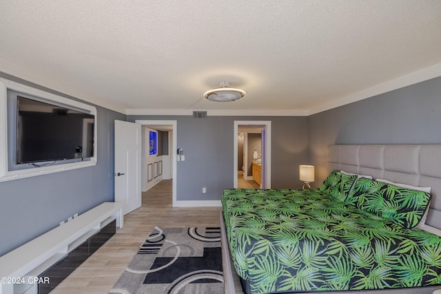 bedroom featuring a textured ceiling, baseboards, visible vents, and light wood-style floors