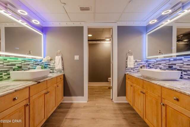 bathroom with backsplash, vanity, toilet, and wood-type flooring