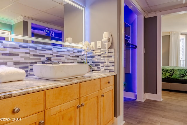 bathroom with vanity, tasteful backsplash, hardwood / wood-style floors, and a drop ceiling