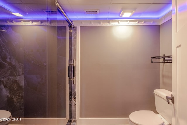 bathroom featuring a shower with shower door and toilet