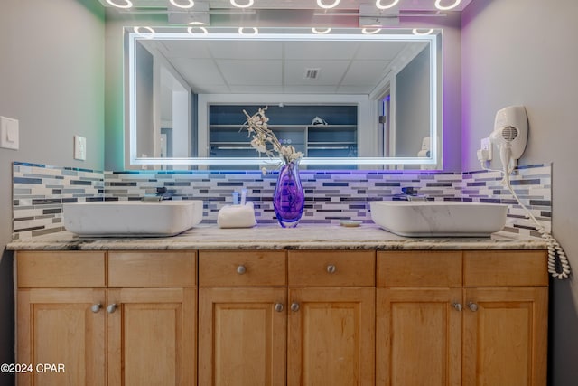 full bathroom featuring double vanity, tasteful backsplash, and a sink