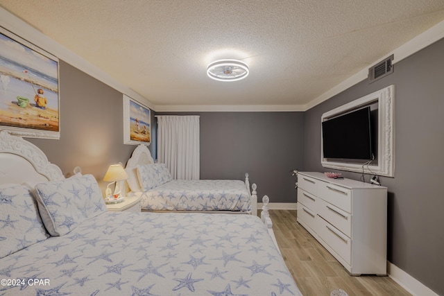 bedroom with light wood-type flooring, visible vents, a textured ceiling, and baseboards