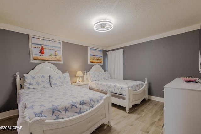 bedroom with light wood-style floors, baseboards, and a textured ceiling