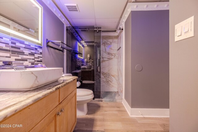 bathroom with backsplash, hardwood / wood-style floors, toilet, a shower with shower door, and vanity