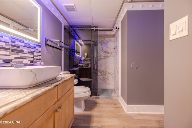 bathroom with a marble finish shower, visible vents, decorative backsplash, toilet, and vanity