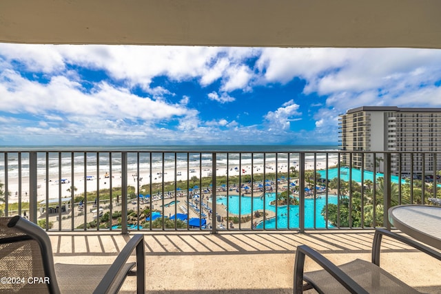 balcony with a water view and a view of the beach