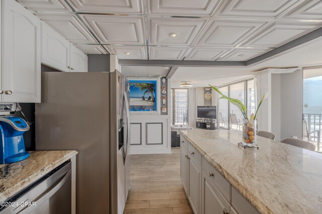 kitchen featuring plenty of natural light, light stone countertops, light wood-type flooring, and white cabinets