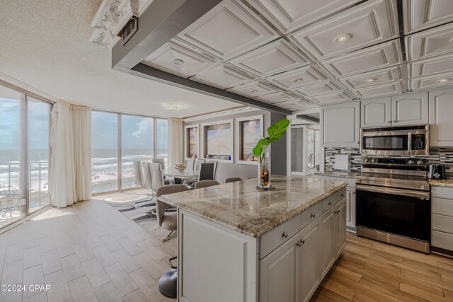 kitchen with a center island, light stone counters, stainless steel appliances, and light hardwood / wood-style flooring