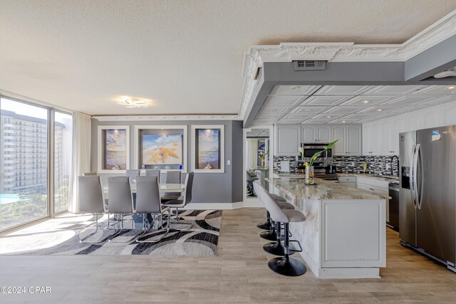 dining space with a textured ceiling, light hardwood / wood-style flooring, and ornamental molding