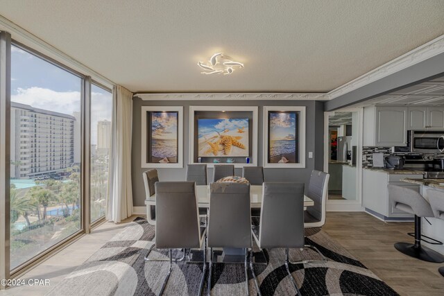 dining room featuring light wood-type flooring, a textured ceiling, and a wall of windows