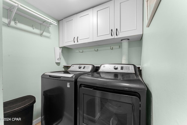 clothes washing area with washer and clothes dryer and cabinets