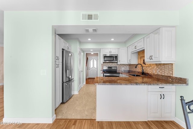 kitchen featuring light hardwood / wood-style floors, white cabinets, kitchen peninsula, stainless steel appliances, and sink