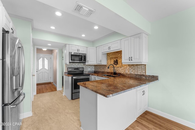 kitchen with light hardwood / wood-style floors, sink, white cabinetry, kitchen peninsula, and appliances with stainless steel finishes