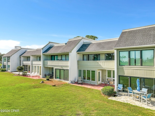 rear view of house with a patio, a yard, and a balcony