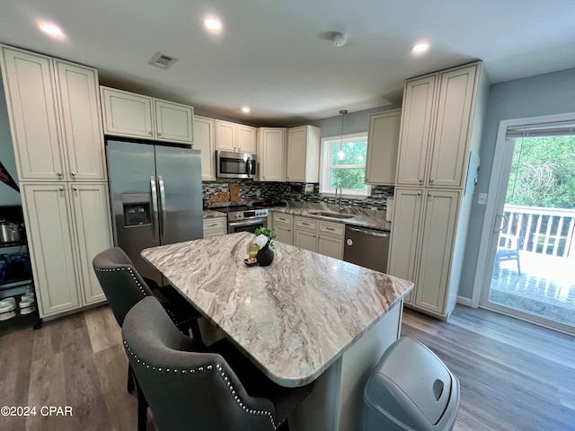 kitchen featuring pendant lighting, hardwood / wood-style floors, appliances with stainless steel finishes, and a kitchen island