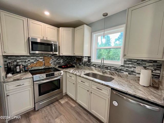 kitchen featuring sink, light hardwood / wood-style flooring, white cabinetry, appliances with stainless steel finishes, and light stone countertops