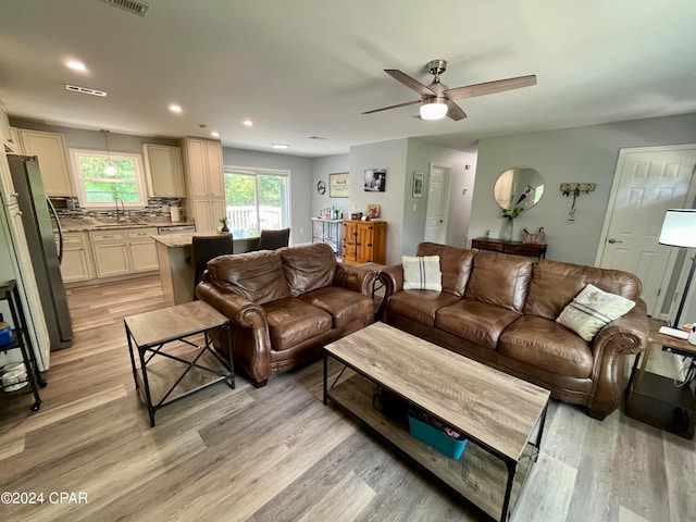 living room with light wood-type flooring, sink, and ceiling fan