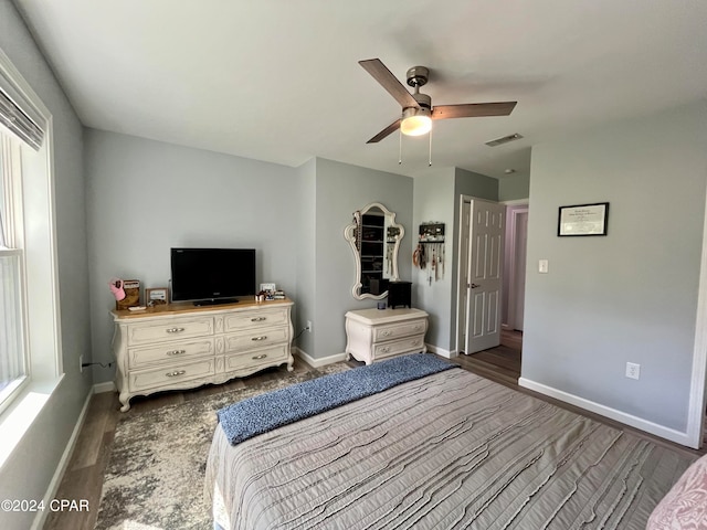 unfurnished bedroom with ceiling fan, multiple windows, and dark wood-type flooring