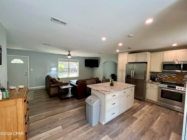 kitchen with white cabinets, appliances with stainless steel finishes, light hardwood / wood-style floors, and a center island