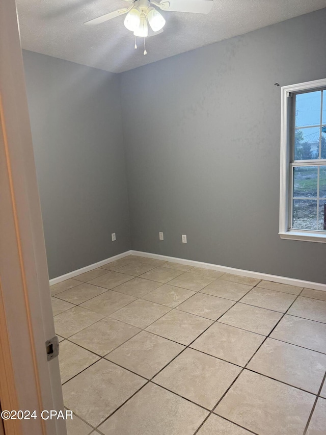 tiled empty room with ceiling fan and a textured ceiling