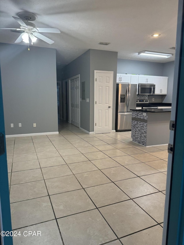 kitchen featuring ceiling fan, light tile patterned flooring, a textured ceiling, white cabinetry, and appliances with stainless steel finishes