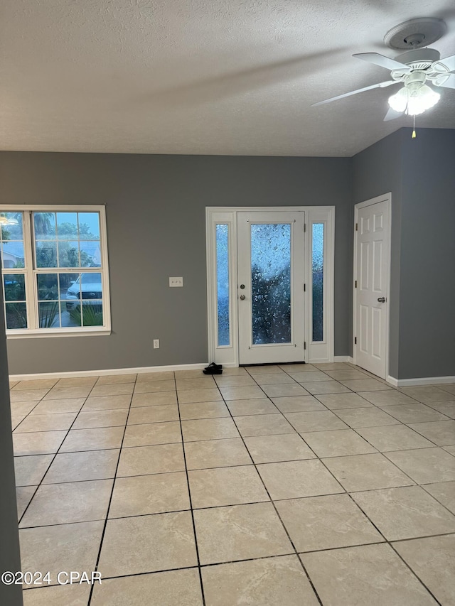 tiled empty room featuring ceiling fan and a textured ceiling