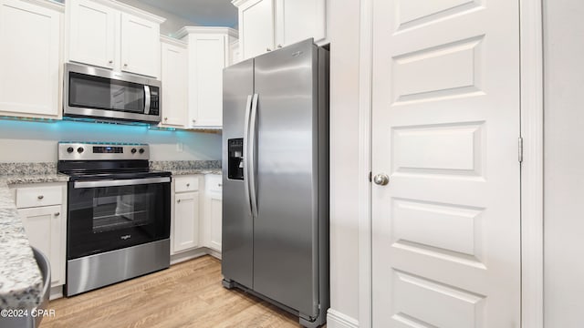 kitchen featuring light hardwood / wood-style floors, white cabinetry, stainless steel appliances, and light stone counters