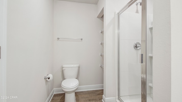 bathroom featuring hardwood / wood-style flooring, toilet, and a shower with door