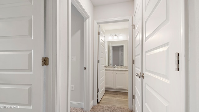 corridor featuring sink and light hardwood / wood-style floors