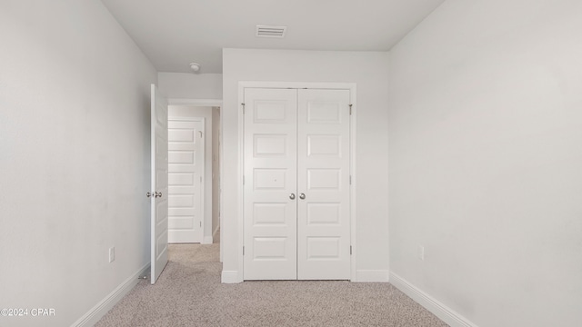 unfurnished bedroom with a closet and light colored carpet