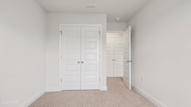 unfurnished bedroom with light colored carpet and a closet