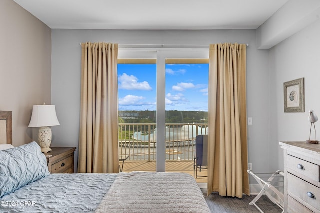 bedroom featuring hardwood / wood-style floors, access to exterior, and a water view