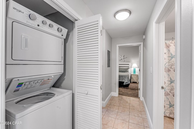 washroom with light tile patterned floors, stacked washer / dryer, and electric panel