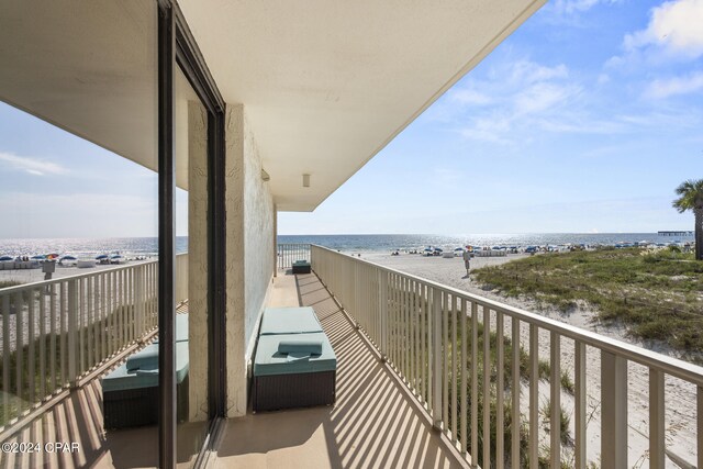 balcony with a water view and a view of the beach