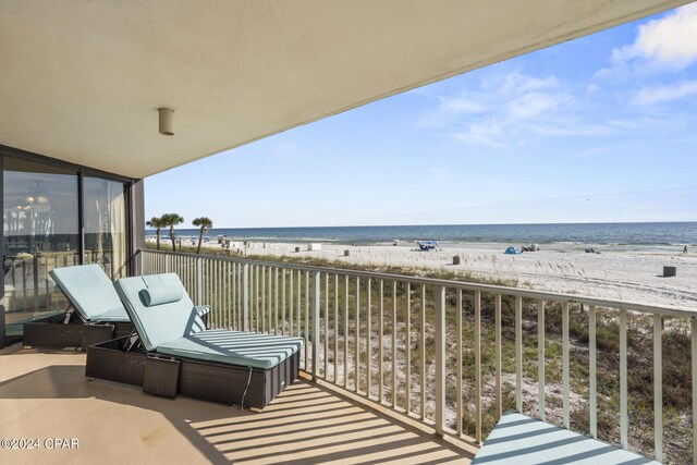 balcony featuring a view of the beach and a water view