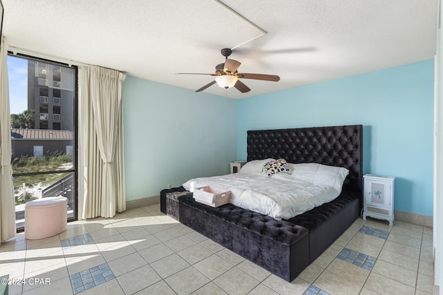 bedroom featuring ceiling fan, light tile patterned floors, and a textured ceiling