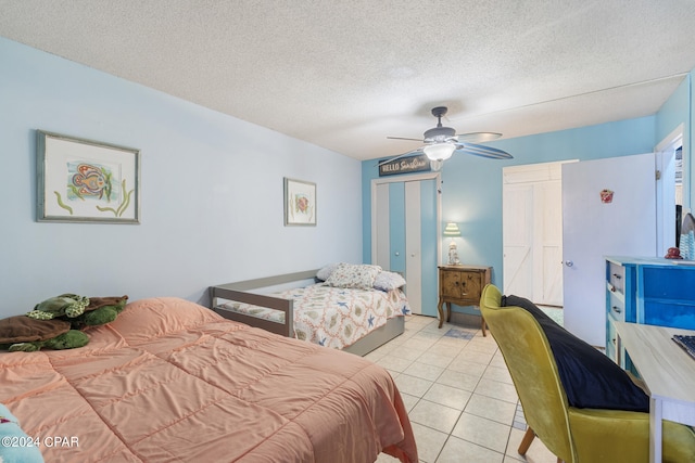 bedroom with ceiling fan, light tile patterned floors, and a textured ceiling