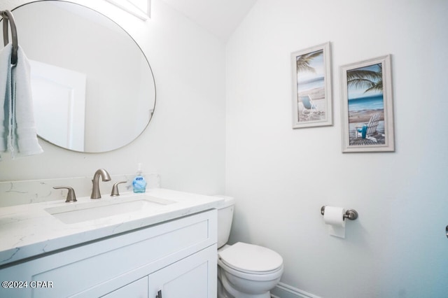 bathroom with lofted ceiling, vanity, and toilet