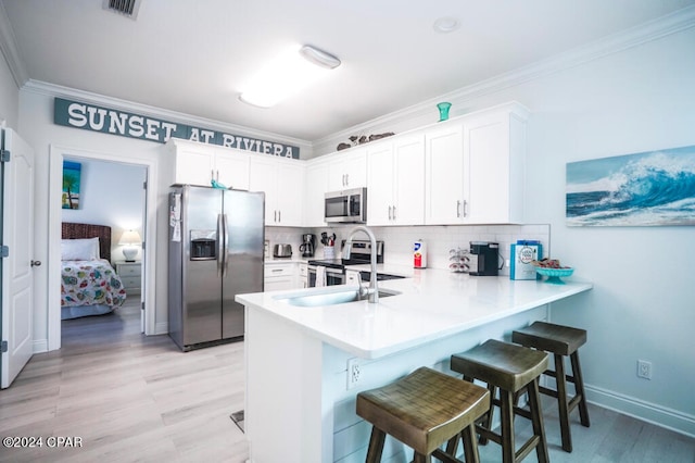 kitchen featuring white cabinetry, kitchen peninsula, appliances with stainless steel finishes, and crown molding