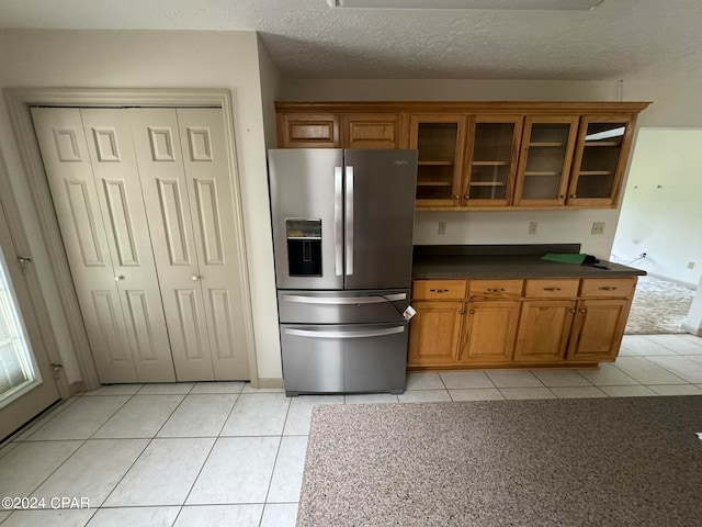 kitchen featuring light tile patterned flooring, stainless steel fridge, and a textured ceiling