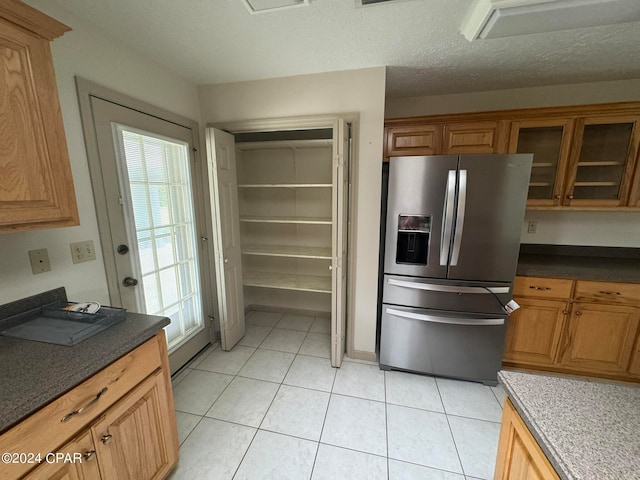 kitchen featuring a textured ceiling, light tile patterned flooring, plenty of natural light, and stainless steel fridge with ice dispenser