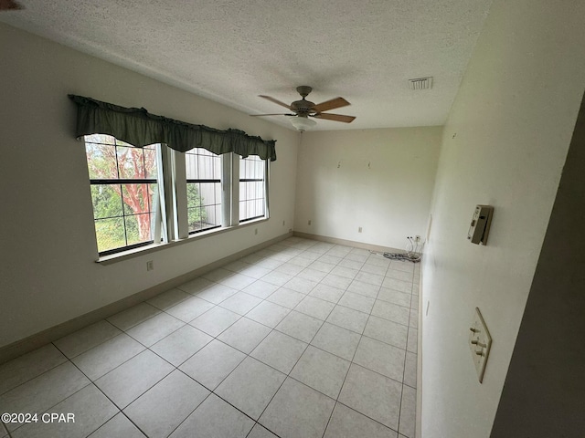 tiled empty room featuring a textured ceiling and ceiling fan