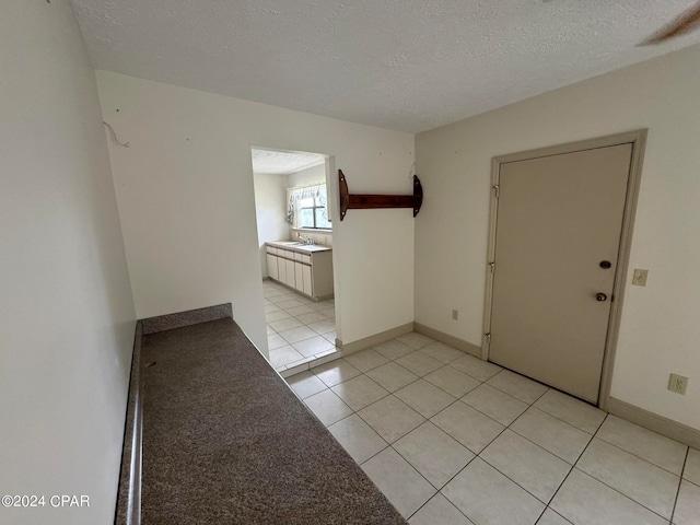 unfurnished room featuring a textured ceiling, sink, and light tile patterned floors