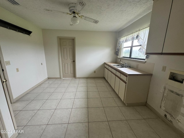 kitchen with ceiling fan, sink, light tile patterned floors, and a textured ceiling