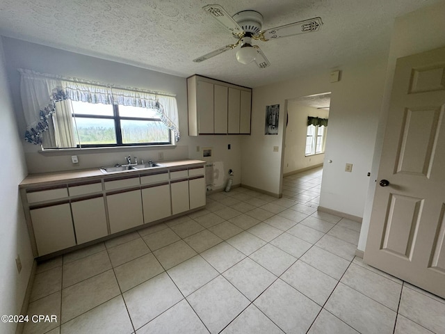 kitchen with a textured ceiling, light tile patterned floors, sink, and ceiling fan