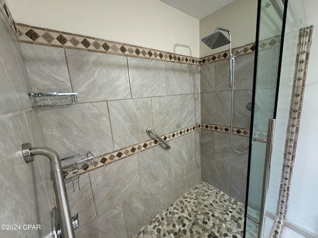 bathroom with walk in shower and a textured ceiling