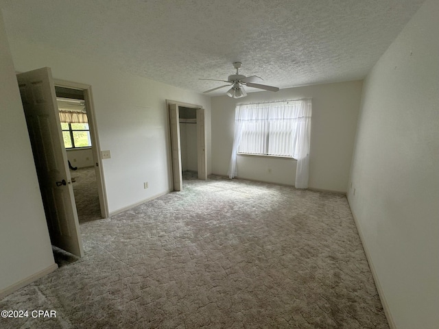 carpeted spare room featuring a textured ceiling and ceiling fan