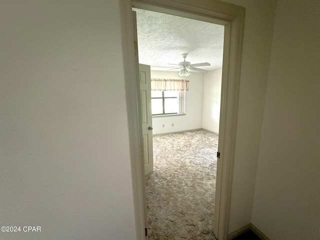 hallway with a textured ceiling and carpet