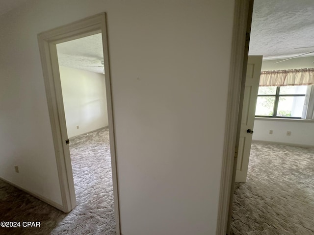 corridor featuring a textured ceiling and carpet floors