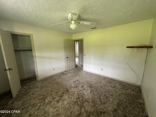 unfurnished bedroom with ceiling fan, a textured ceiling, a closet, and dark colored carpet